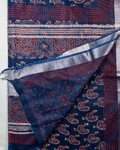 A folded and draped blue patterned cotton shawl or scarf with red and cream motifs, shown against a light background with a brand logo and text at the bottom.